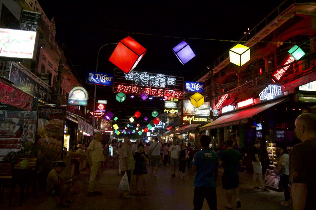 A neon sign saying 'Pub Street' glows brightly above a pedestrian packed street in Siem Reap.