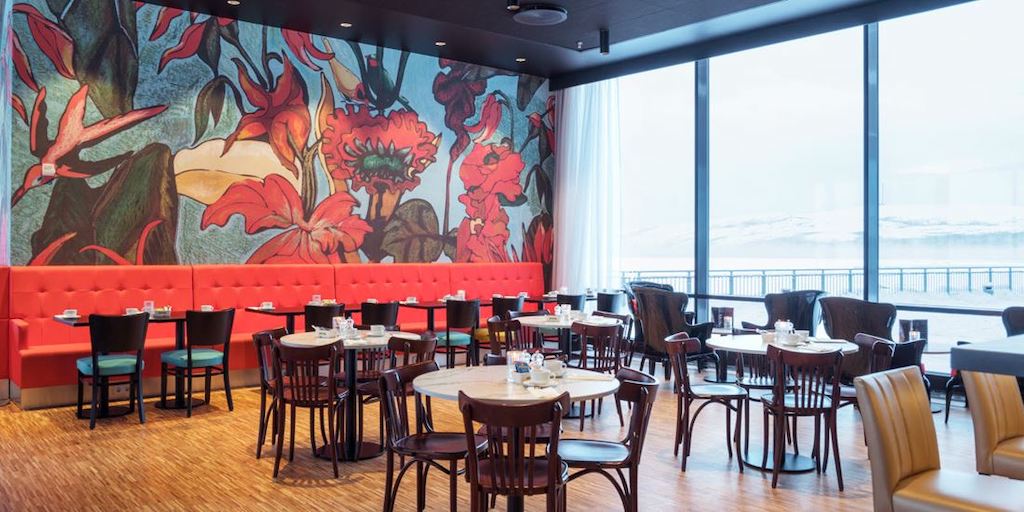 The brightly coloured dining area at the Thon Hotel Kirkenes. A floor to ceiling window looks out over the Arctic Ocean.